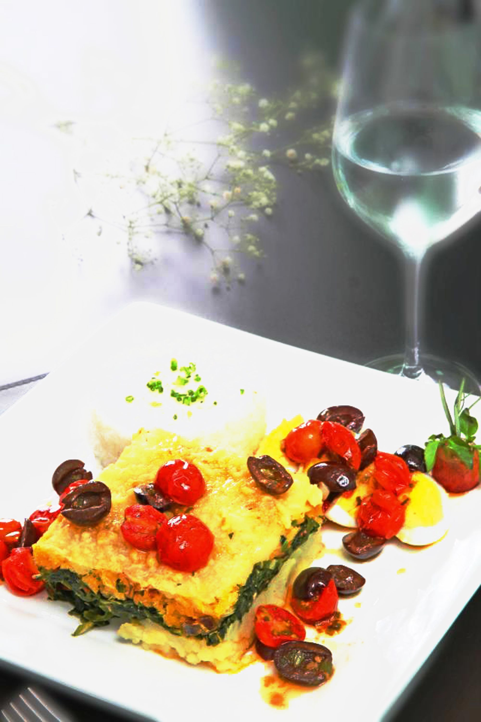 Un plat composé de légumes verts, de tomates et d’olives, servi dans une assiette blanche.