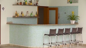 A reception area with a tiled wall, a counter with shelves of bottles, and four bar stools.