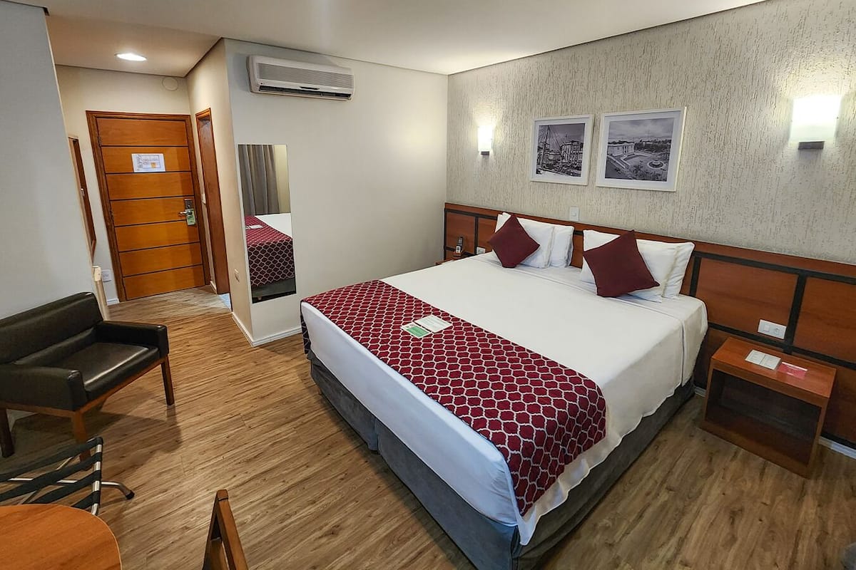 Ein Hotelzimmer mit Bett, Nachttischen, Schreibtisch, Stuhl, Spiegel und Tür.
