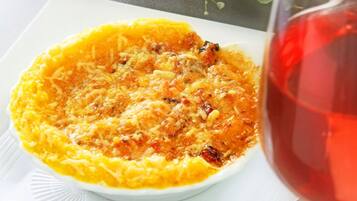 Une assiette blanche contenant un plat cuit au four, un verre de vin rouge et une fourchette posée sur une serviette blanche.