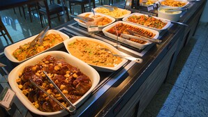 A buffet with various dishes, including meats and salads, arranged on a buffet line.