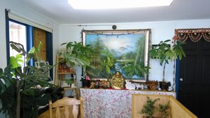 Una habitación con un escritorio de madera, una silla, un cuadro grande y varias plantas en macetas.