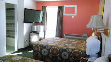 A hotel room with a bed, a television, a microwave, and a heater.