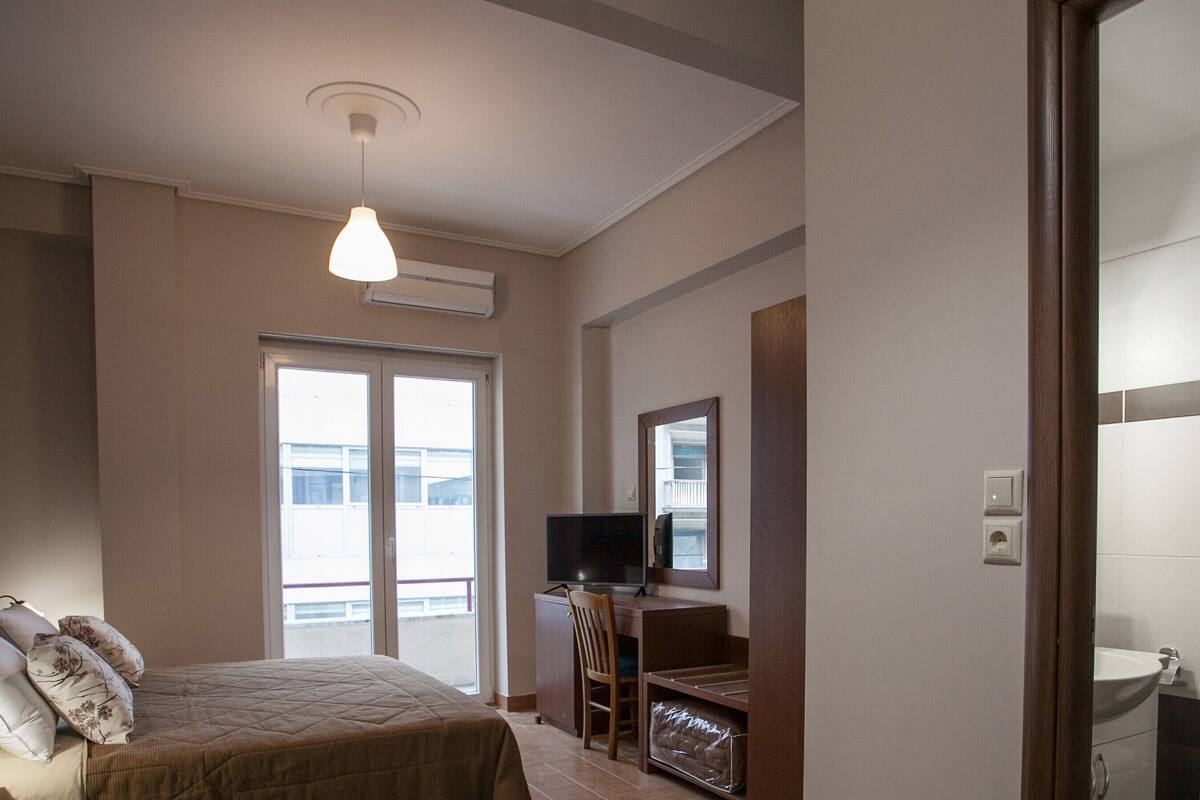 A hotel room with a bed, a TV, a desk, and a bathroom.