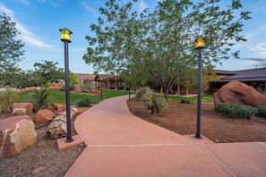 A pathway leading to a building with a rustic exterior, surrounded by large rocks and trees.