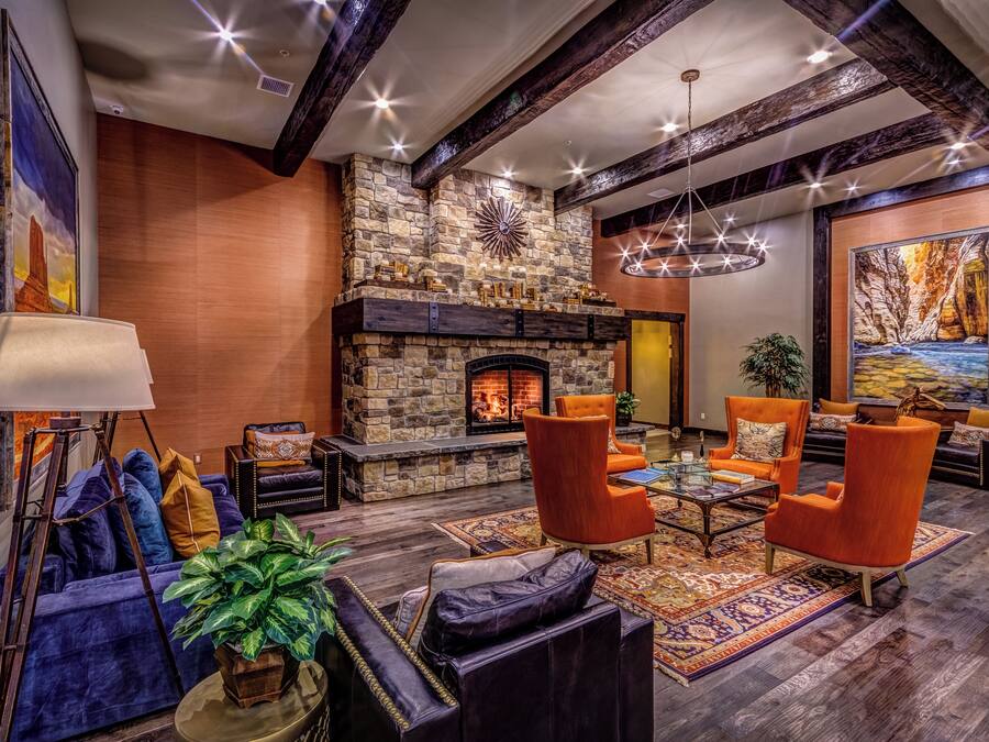 A cozy living room with a stone fireplace, orange armchairs, and a large painting on the wall.