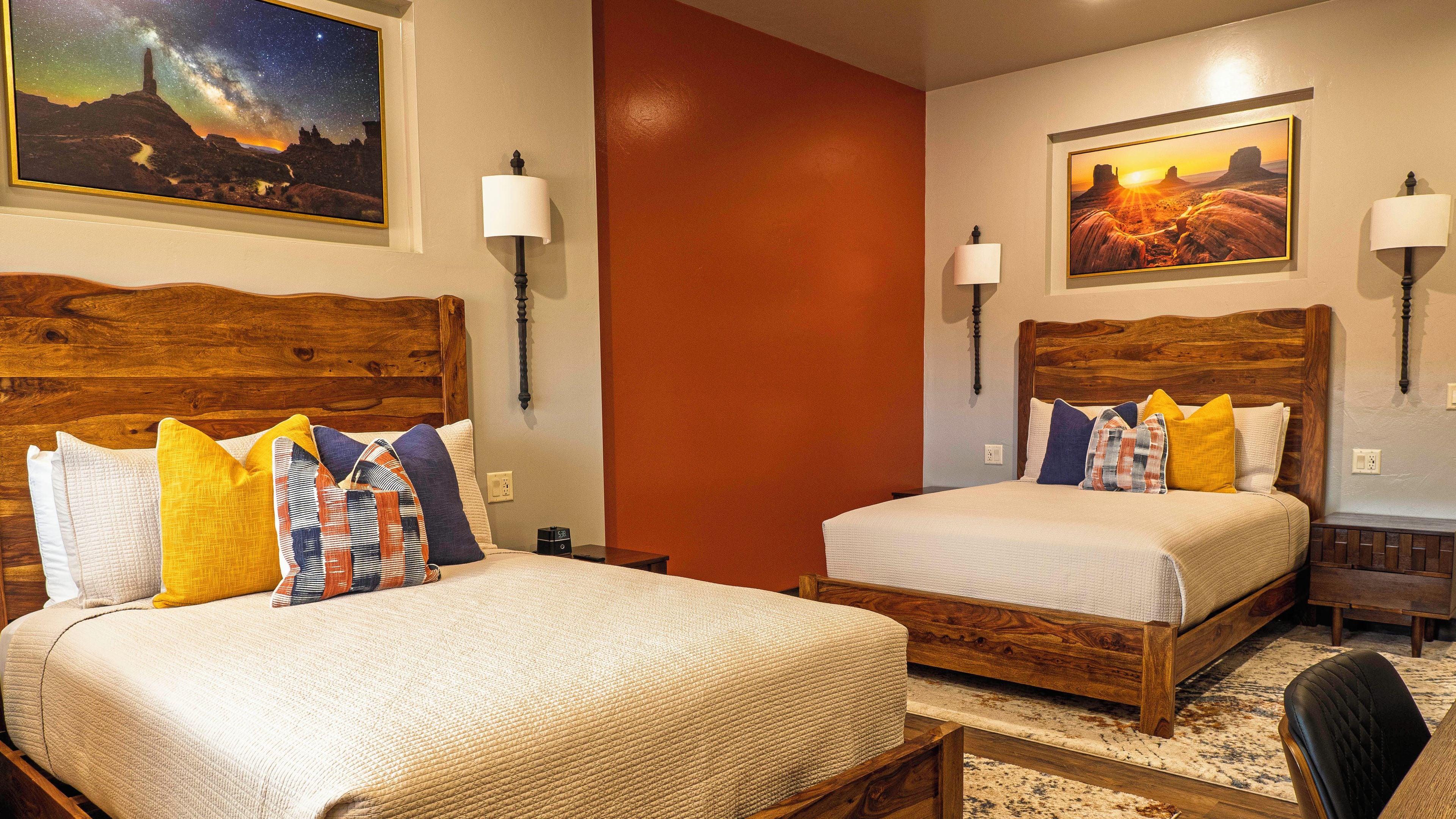 A hotel room with two beds, wooden headboards, and wall-mounted lamps.