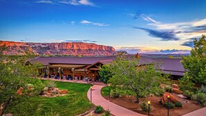 A lodge with a covered patio, a landscaped garden, and views of red rock formations. - Desert Rose Resort & Cabins (Bluff)