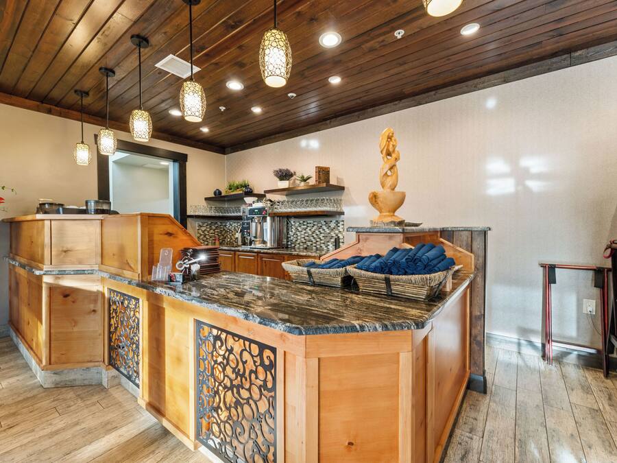 A kitchen with wooden cabinets, a granite countertop, hanging pendant lights, and a decorative sculpture.