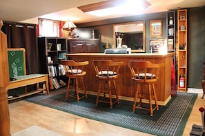A bar area with wooden chairs, a counter, and a bookshelf. - The Findlay House (Collingwood)