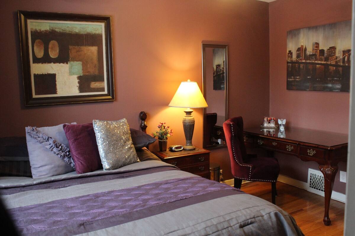 Een hotelkamer met een bed, een bureau, een stoel, een lamp en kunst aan de muren.