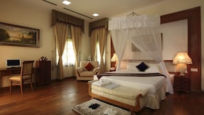 Une chambre à coucher avec un lit à baldaquin, un bureau avec un ordinateur, une chaise et une table de chevet avec une lampe.