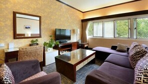A hotel room with a sofa, armchairs, a coffee table, a TV, and a window with curtains. - Cingjing Guest House (Ren'ai)