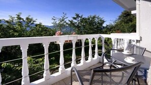 A balcony with a white railing, a table with chairs, and a view of greenery and mountains. - Cingjing Guest House (Ren'ai)