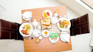 Una mesa de comedor dispuesta con platos de comida, tazas y cubiertos en una habitación de hotel.