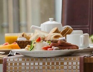 A breakfast setting with a plate of eggs, sausages, toast, and a cup of coffee. - Birdrock Hotel (Anomabo)