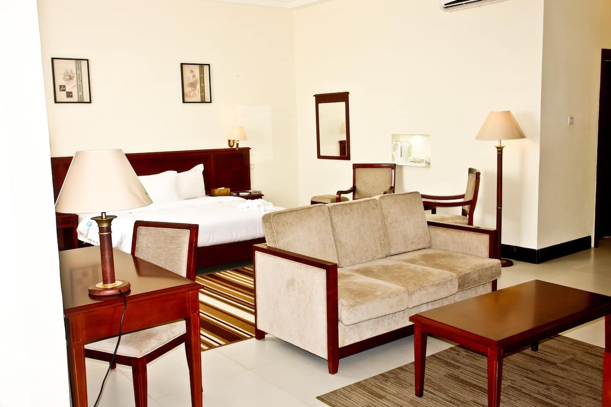 A hotel room with a bed, a sofa, a desk, and a chair.
