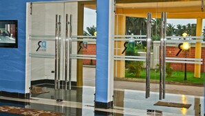 Entrada de hotel con puertas de vidrio, pared azul y un espacio exterior con vegetación.