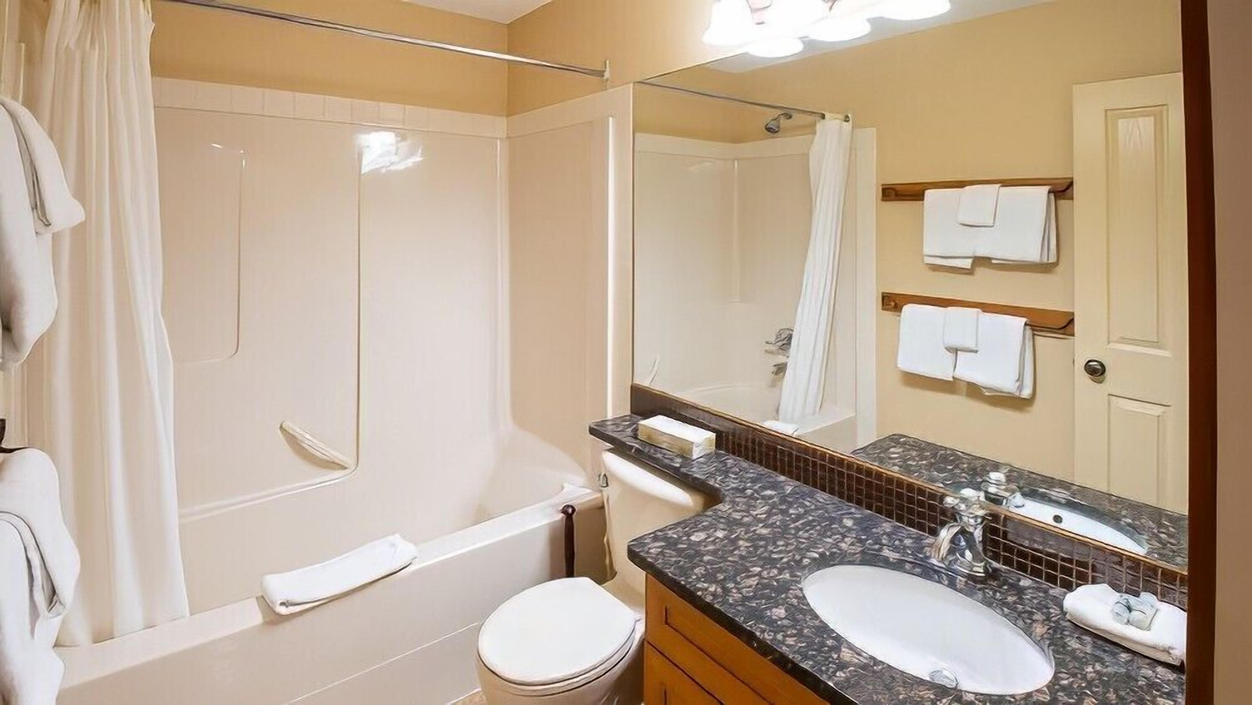 A bathroom with a bathtub, a toilet, a sink, and a large mirror.