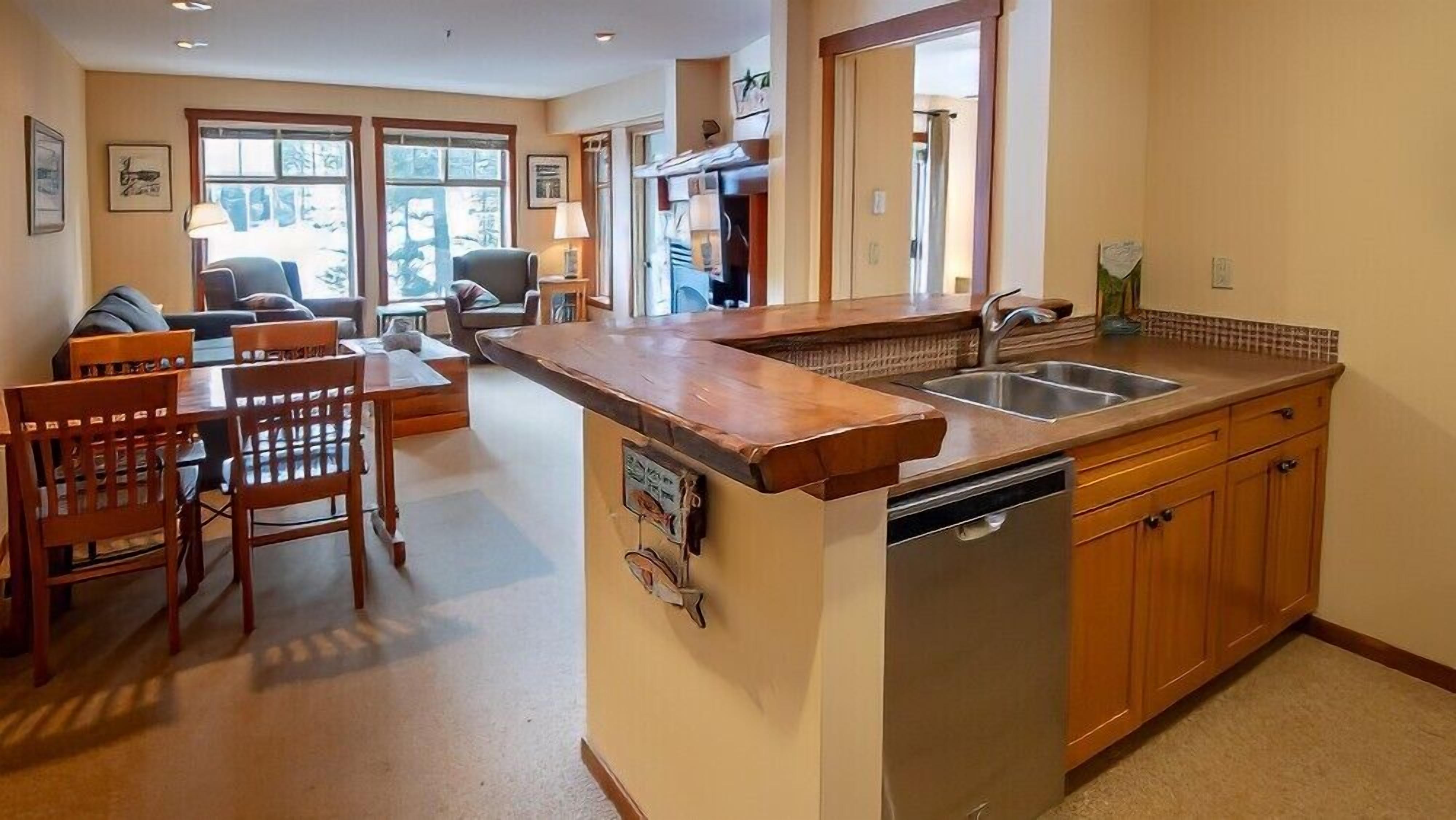 A kitchen with wooden cabinets, a built-in dishwasher, and a large island with a sink.