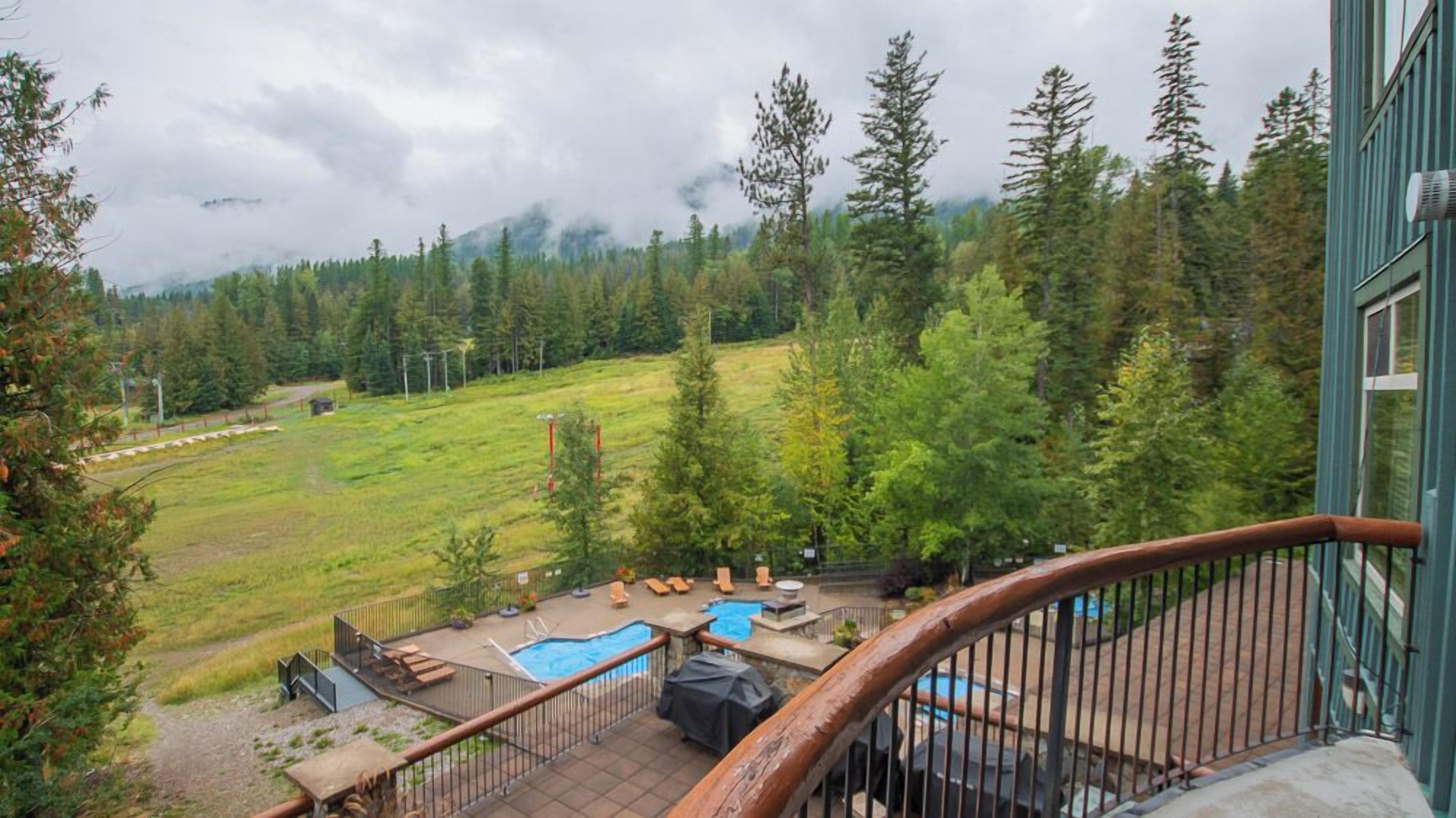 A view from a balcony overlooking a pool area with a mountain backdrop.