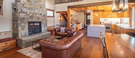 A spacious living area with a stone fireplace, leather sectional sofa, and a wooden dining table.