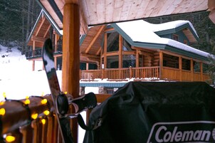 Una cabaña de troncos con balcón y techo cubierto de nieve.