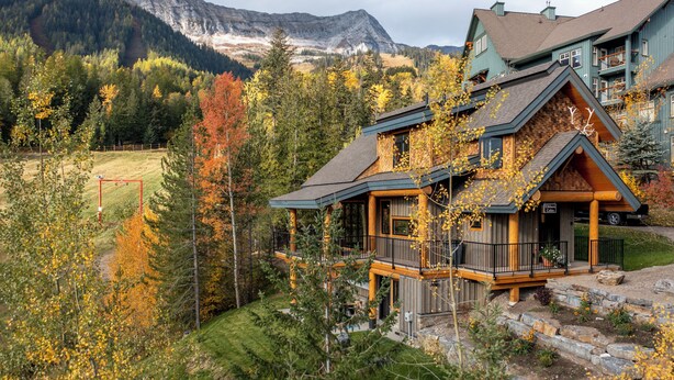 Ein mehrstöckiges Holzhaus mit Balkon und Blick auf eine Berglandschaft.