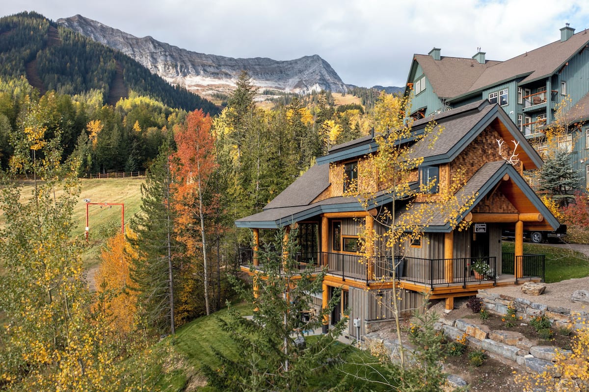 Ein mehrstöckiges Holzhaus mit Balkon und Blick auf eine Berglandschaft.