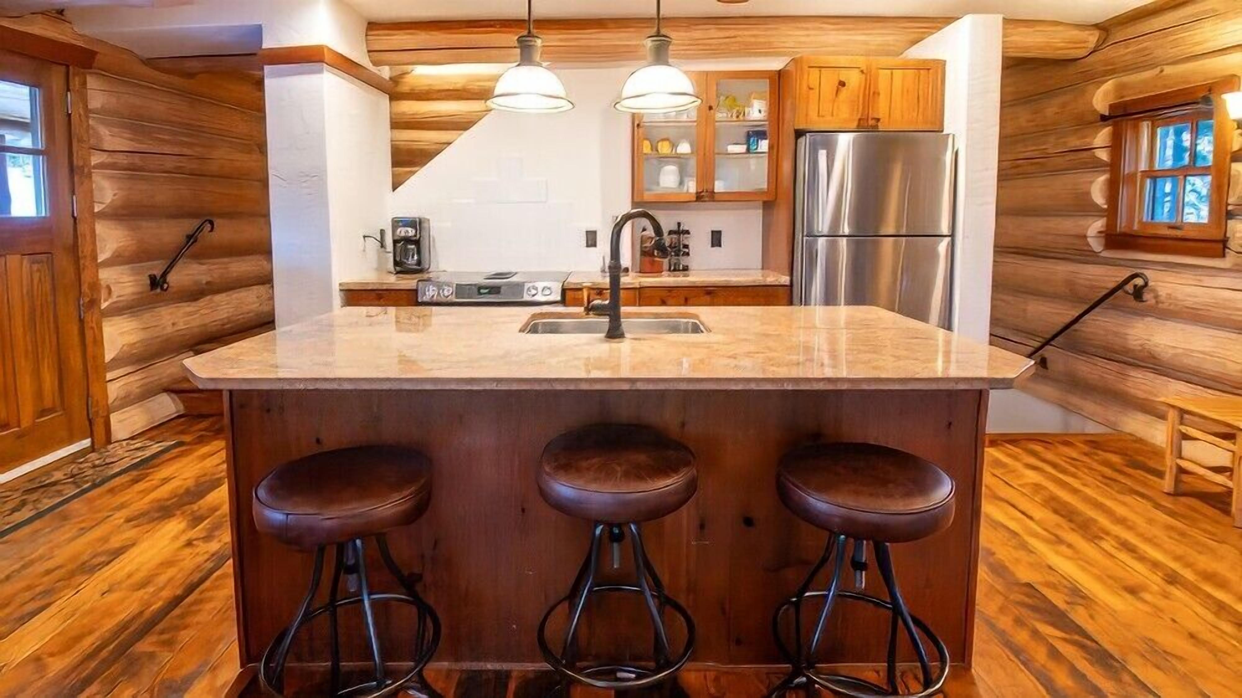 A kitchen with a central island, wooden cabinets, stainless steel appliances, and a window.