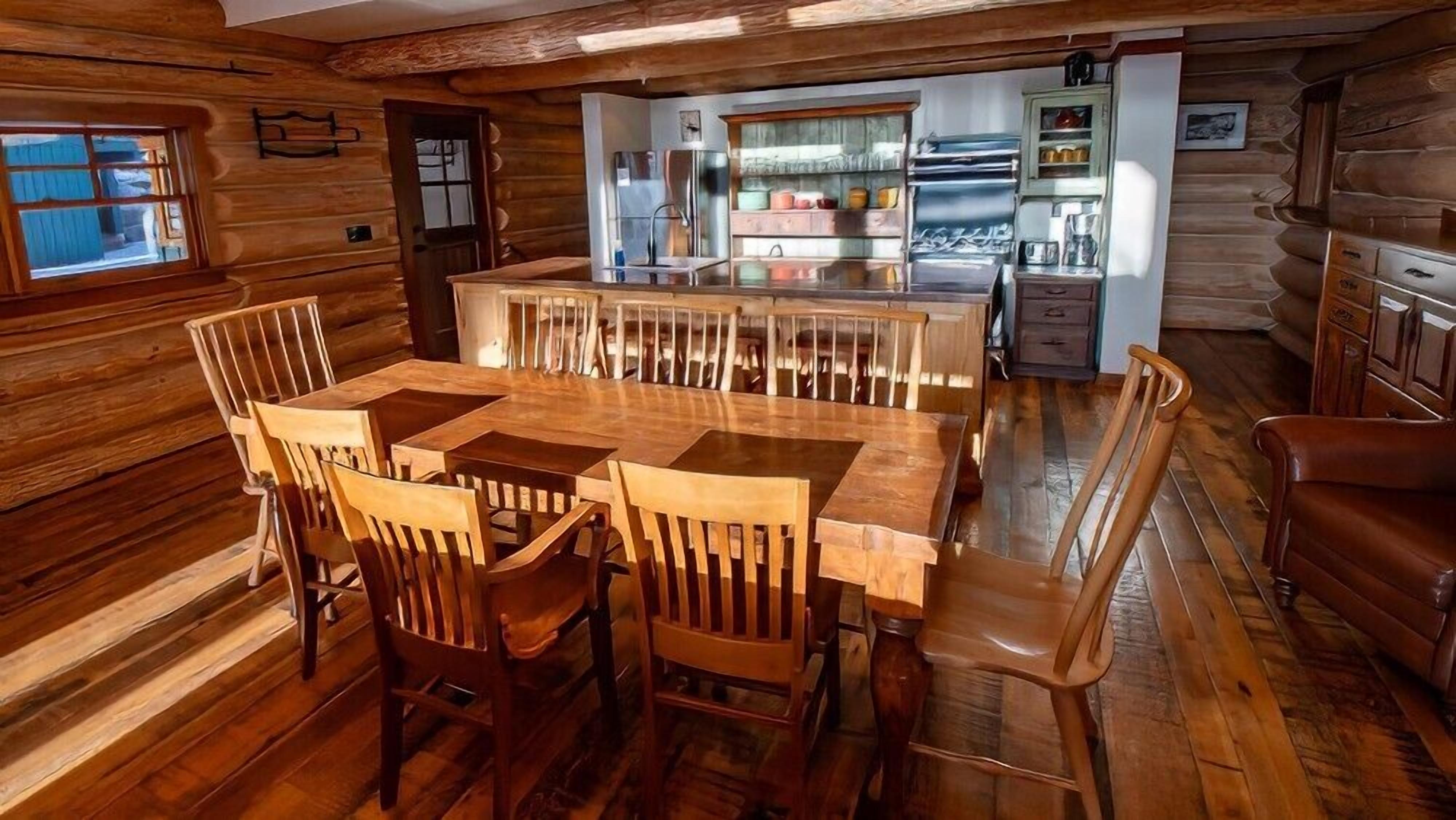 A wooden cabin interior with a dining area, kitchen, and a cozy living space.