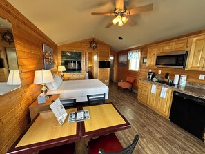 Une pièce confortable, aménagée comme un chalet, avec un lit, une table à manger et un coin cuisine.