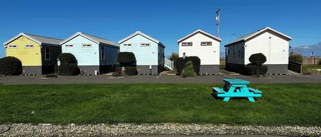 A row of colorful mobile homes numbered 19 to 23, with a picnic table in the foreground.