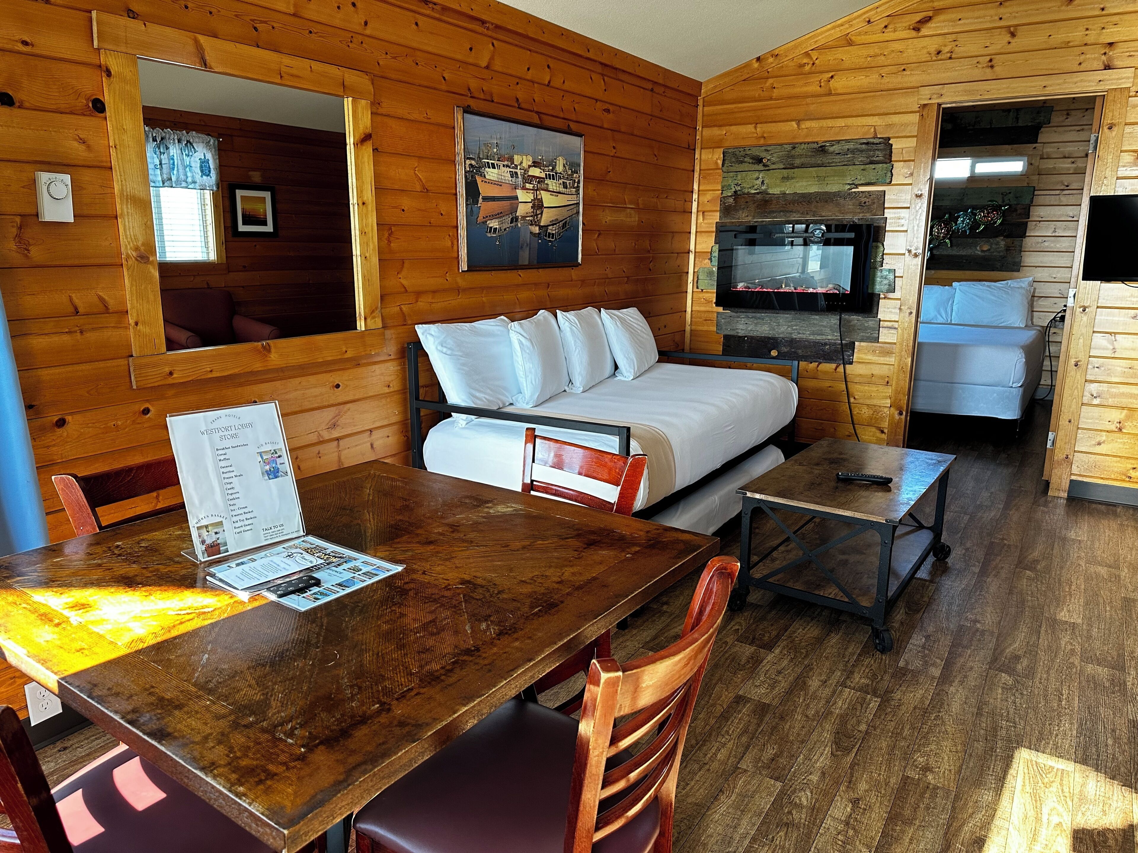A wooden cabin with a bed, a sofa, a dining table, and a TV.