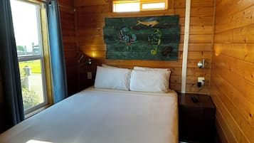 A wooden cabin room with a bed, a window, and a wall decorated with fish.