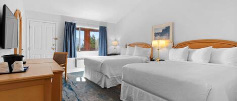 A hotel room with two beds, a desk with a mirror, a chair, and a painting on the wall.