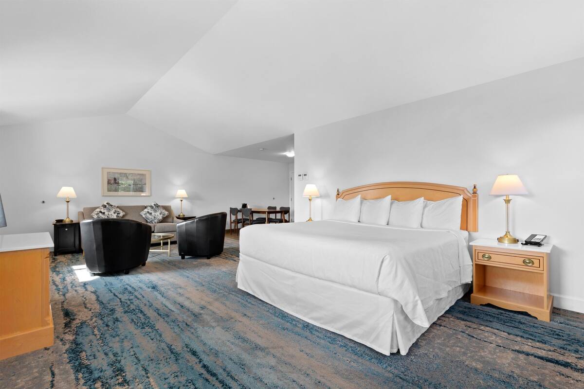Une chambre d’hôtel avec un grand lit, deux tables de chevet avec des lampes, un canapé, un bureau et une chaise.