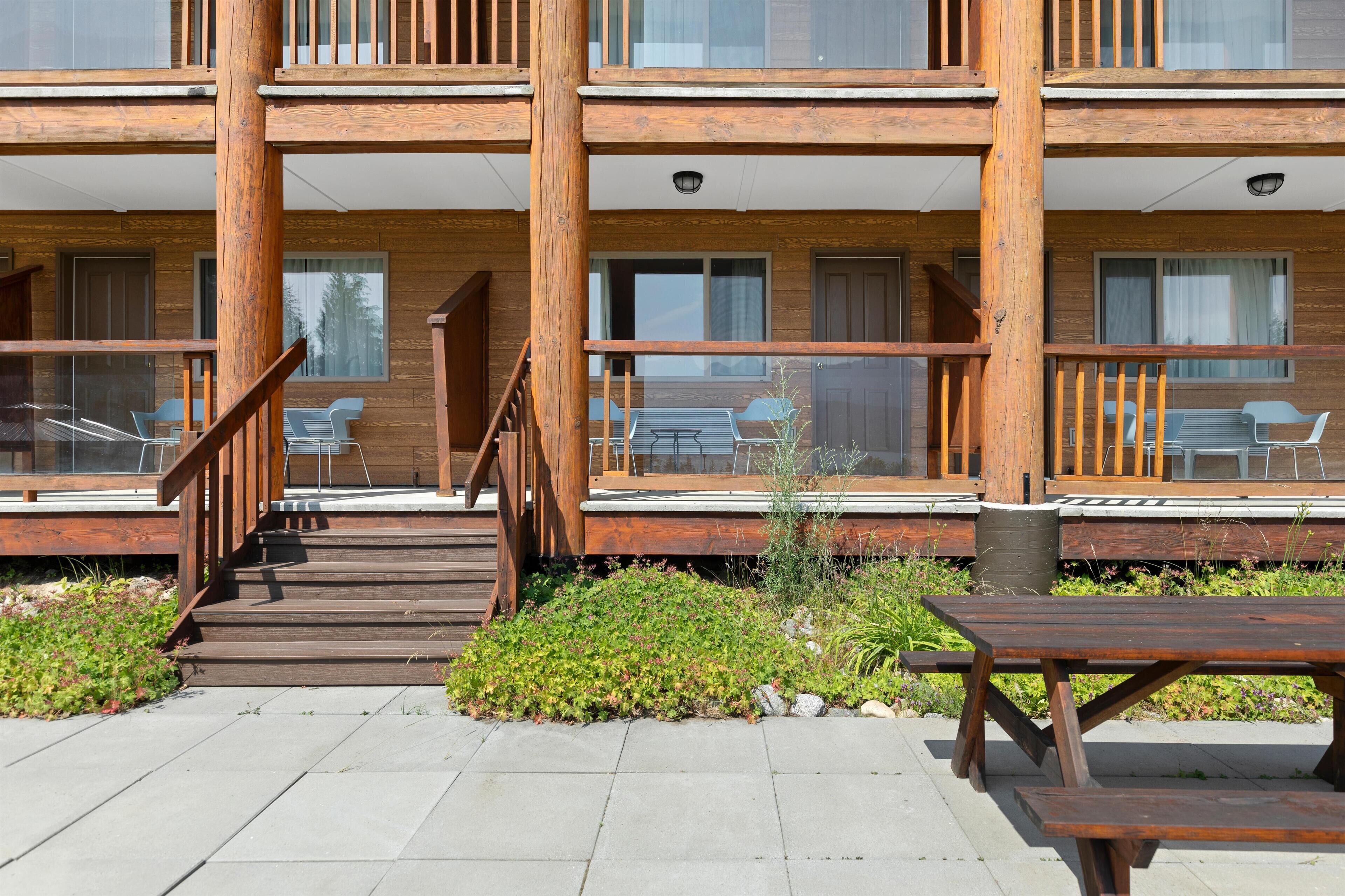 Un edificio de madera de varios pisos con asientos al aire libre y una escalera que conduce a la entrada.