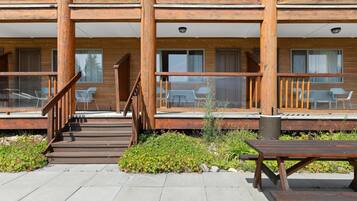 A multi-story wooden building with outdoor seating and a staircase leading to the entrance.