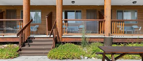 A multi-story wooden building with outdoor seating and a staircase leading to the entrance.
