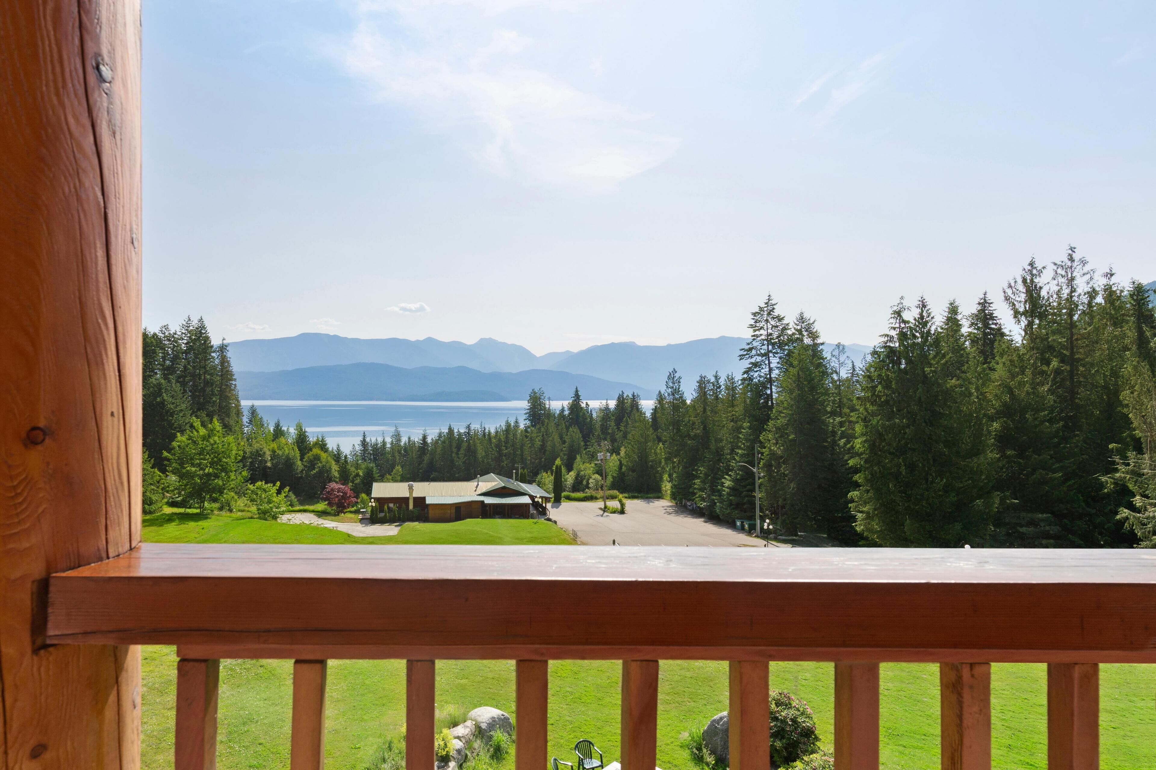 A wooden deck with a view of a mountain range and a lake.