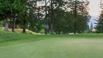 Un parcours de golf avec un mât de drapeau, des arbres et un panneau indicateur.
