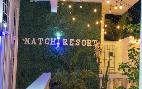 A wall with 'MATCH RESORT' written on it, surrounded by greenery and string lights.