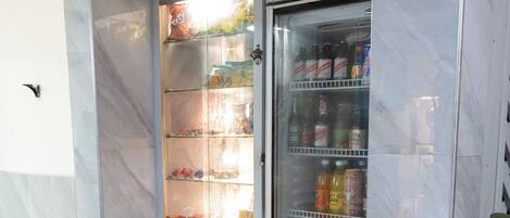 A vending machine with a variety of beverages and snacks, located in a clean, tiled area with marble walls.