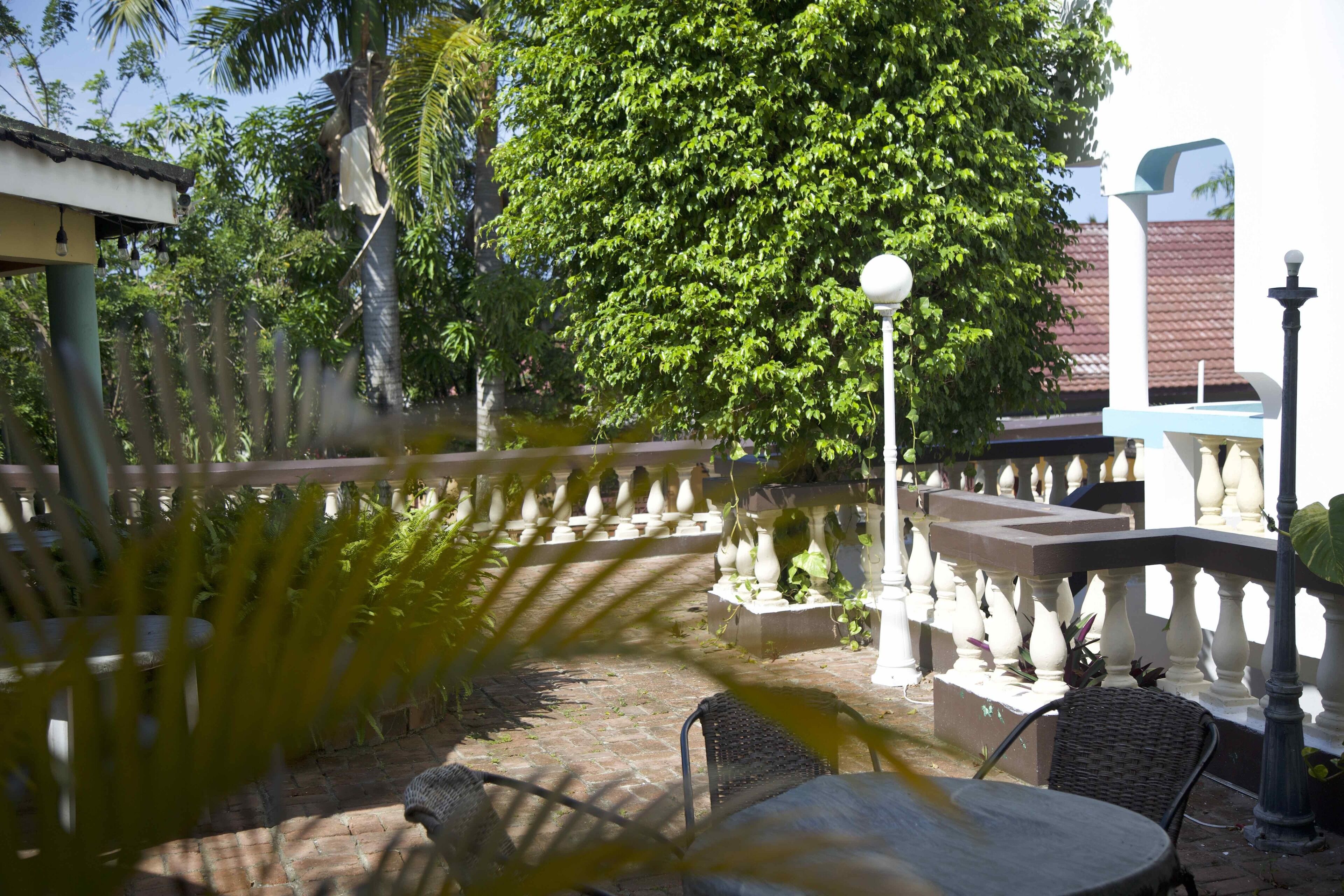 Une terrasse extérieure avec des meubles en osier, un lampadaire et une clôture décorative.
