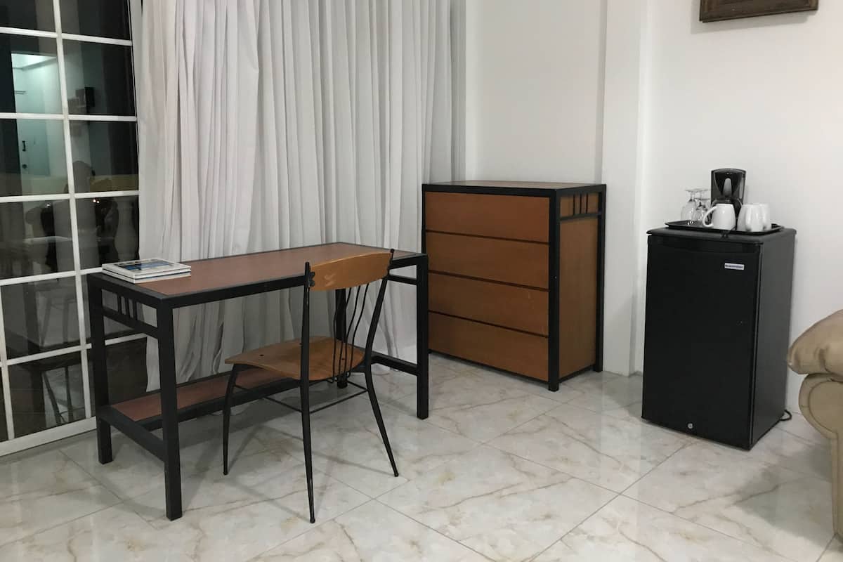 A compact room with a wooden desk, a chair, a cabinet, and a refrigerator.