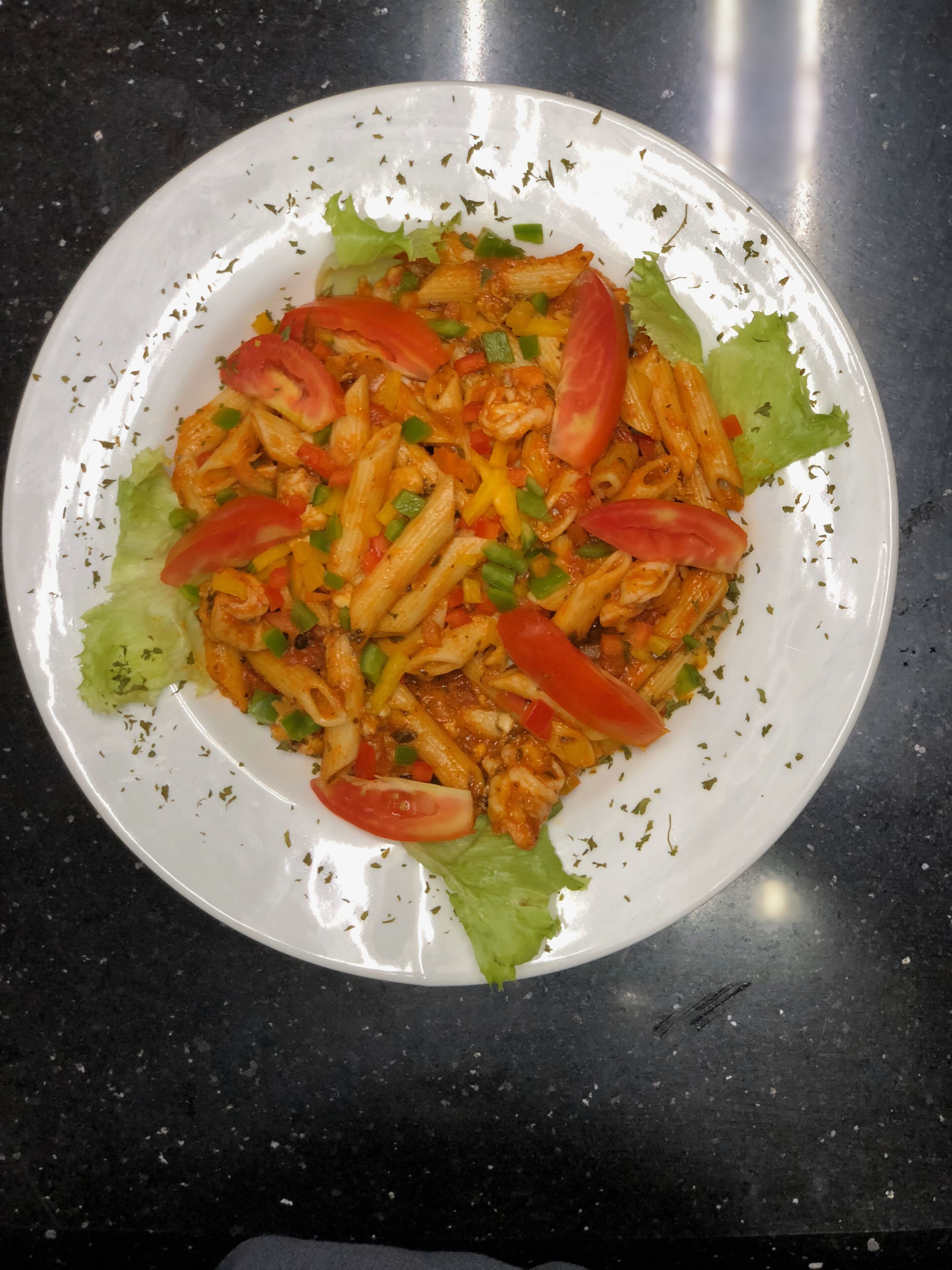A plate of pasta with vegetables and herbs.