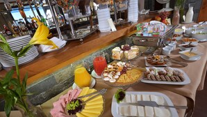 A buffet table with various food items and a flower centerpiece.