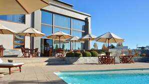 A modern hotel with a swimming pool, outdoor seating, and large umbrellas.