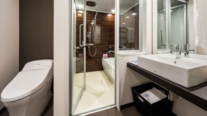 Un baño moderno con inodoro, ducha con mampara de vidrio, lavamanos y espejo.